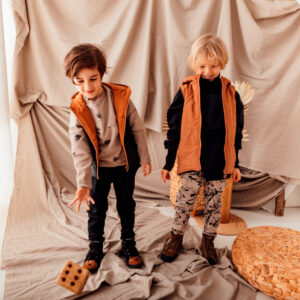 stylizacja dla chłopca: beżowa bluza w misie z czarną kamizelką i czarne spodnie dla chłopca oraz czarna bluza dzięcięca i wzorzyste spodnie dla chłopca